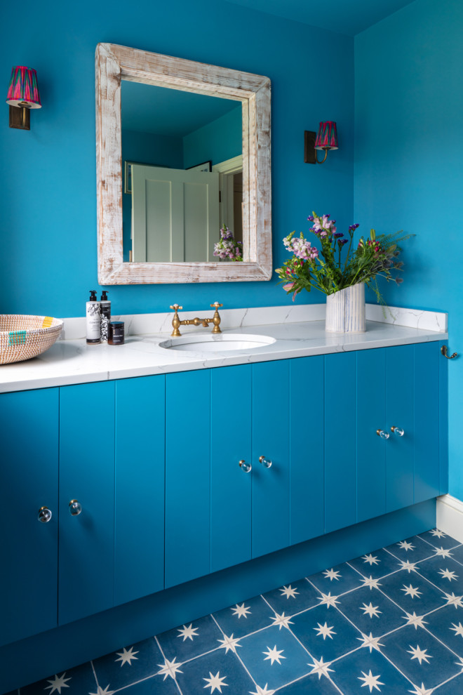 Cette photo montre un grand WC et toilettes avec un mur bleu, carreaux de ciment au sol, un lavabo posé, un plan de toilette en marbre, un sol bleu, un plan de toilette blanc et meuble-lavabo encastré.