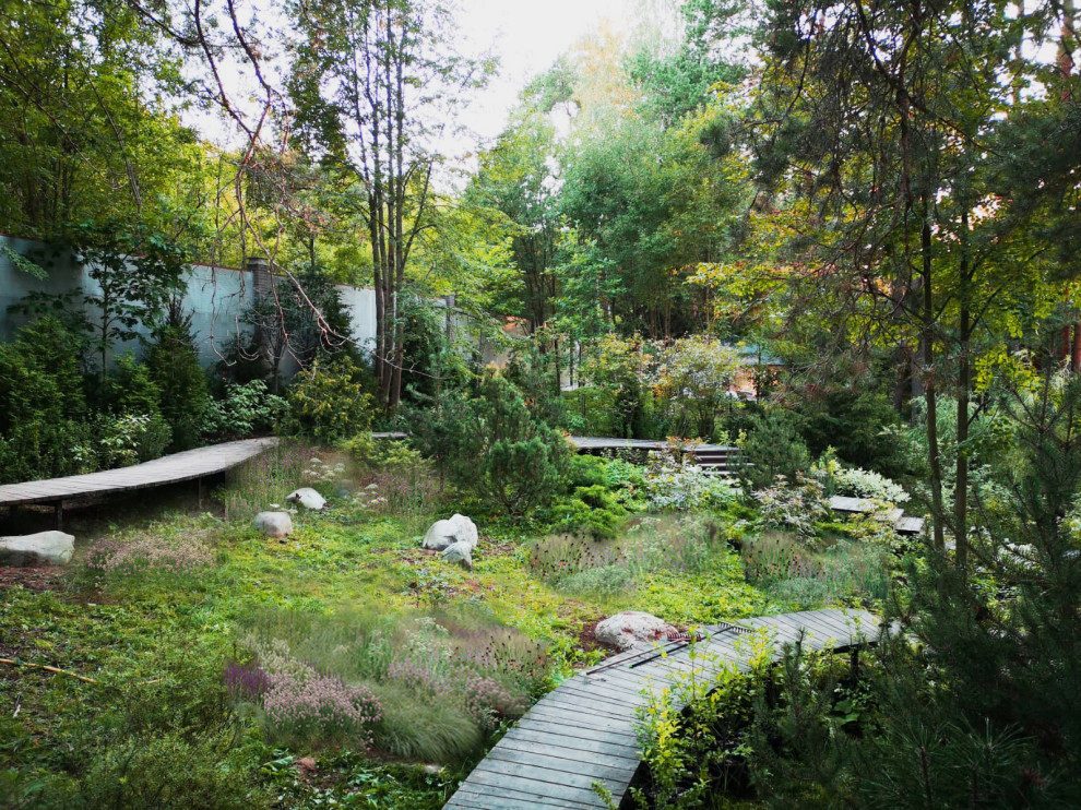 Exemple d'un grand jardin l'été avec pierres et graviers, une exposition ensoleillée, une terrasse en bois et une clôture en pierre.