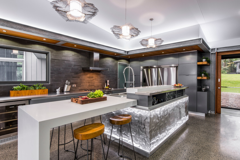 Contemporary l-shaped kitchen in Brisbane with a double-bowl sink, flat-panel cabinets, grey cabinets, stainless steel benchtops, grey splashback, ceramic splashback, stainless steel appliances, concrete floors and with island.