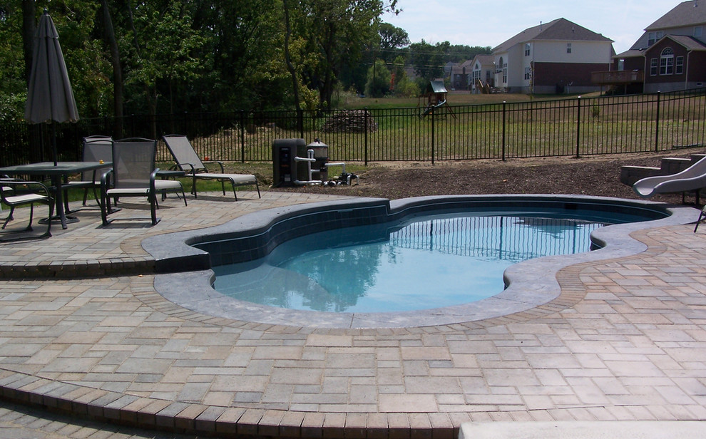 Pool - mid-sized backyard brick and custom-shaped natural pool idea in Cincinnati
