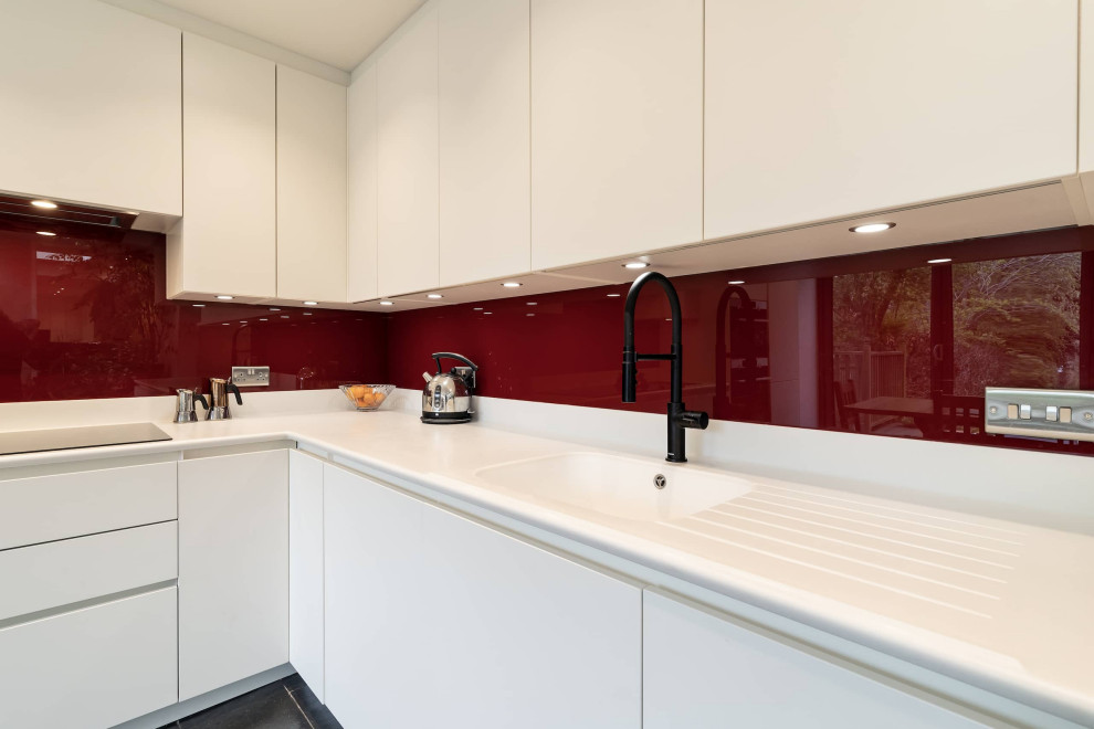 Idéer för att renovera ett mellanstort vintage vit vitt kök, med en integrerad diskho, vita skåp, rött stänkskydd, glaspanel som stänkskydd, rostfria vitvaror, klinkergolv i keramik och svart golv