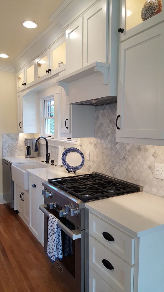 Inspiration for a mid-sized traditional eat-in kitchen in Seattle with a farmhouse sink, recessed-panel cabinets, white cabinets, quartzite benchtops, grey splashback, stone tile splashback, stainless steel appliances, medium hardwood floors and with island.
