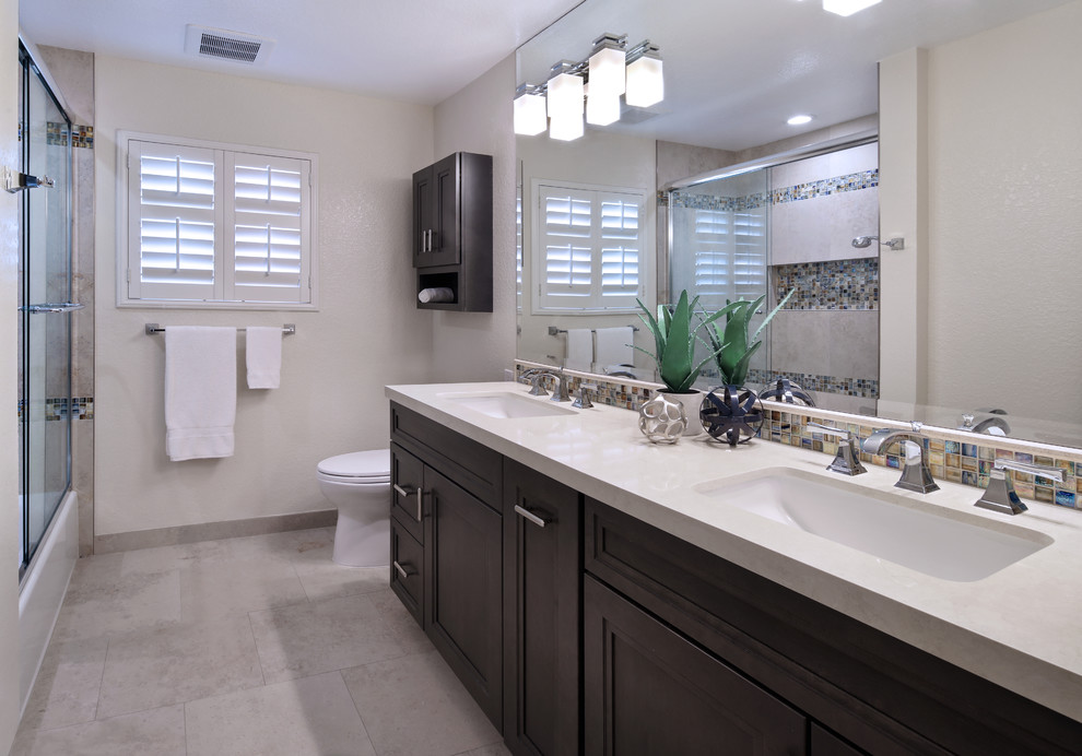 Mid-sized transitional kids bathroom in Orange County with shaker cabinets, medium wood cabinets, an alcove tub, a shower/bathtub combo, a one-piece toilet, beige tile, porcelain tile, beige walls, porcelain floors, an undermount sink and engineered quartz benchtops.