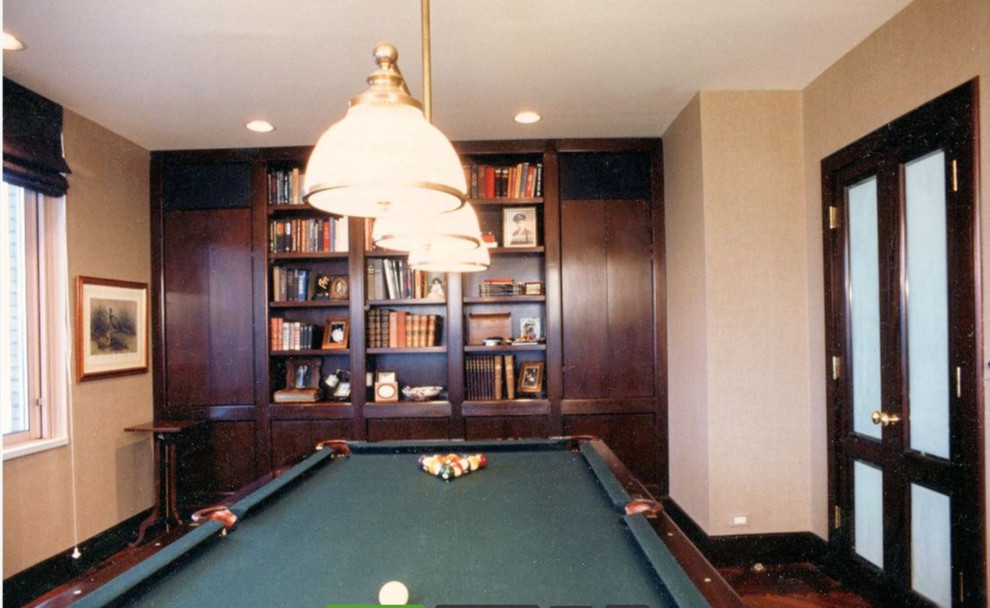 This is an example of a mid-sized traditional enclosed family room in New York with a game room, beige walls, dark hardwood floors and no tv.