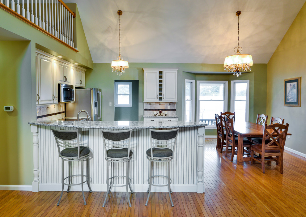 Open concept kitchen - mid-sized transitional galley open concept kitchen idea with a double-bowl sink, beaded inset cabinets, white cabinets, wood countertops, beige backsplash, ceramic backsplash, stainless steel appliances and a peninsula