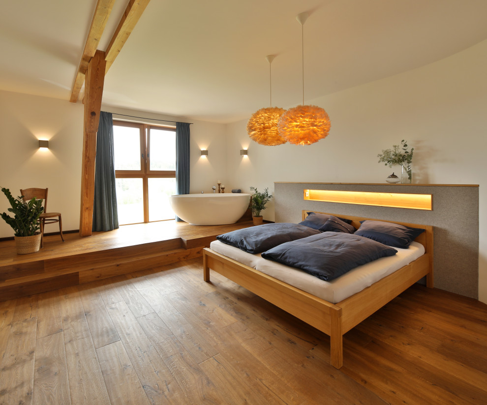 Country Schlafzimmer mit weißer Wandfarbe, braunem Holzboden und braunem Boden in München