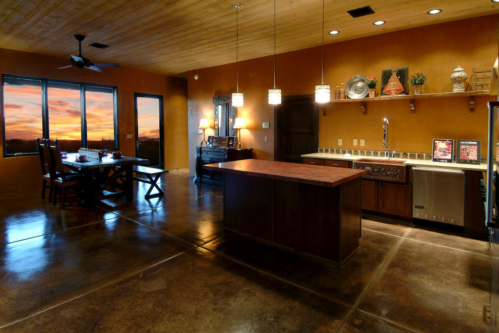 Transitional concrete floor, gray floor and wood ceiling kitchen photo with a farmhouse sink, flat-panel cabinets, brown cabinets, marble countertops, blue backsplash, ceramic backsplash, stainless steel appliances and white countertops