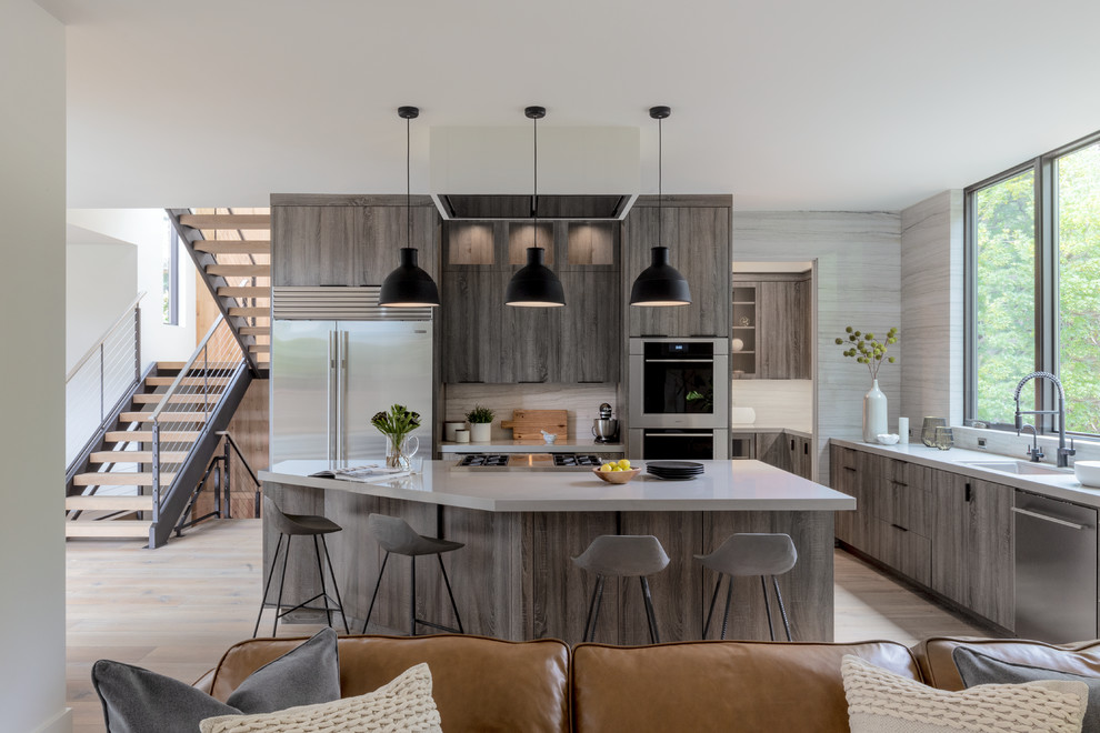 Design ideas for a contemporary l-shaped kitchen in San Francisco with an undermount sink, flat-panel cabinets, grey cabinets, grey splashback, stainless steel appliances, light hardwood floors, with island, beige floor and white benchtop.