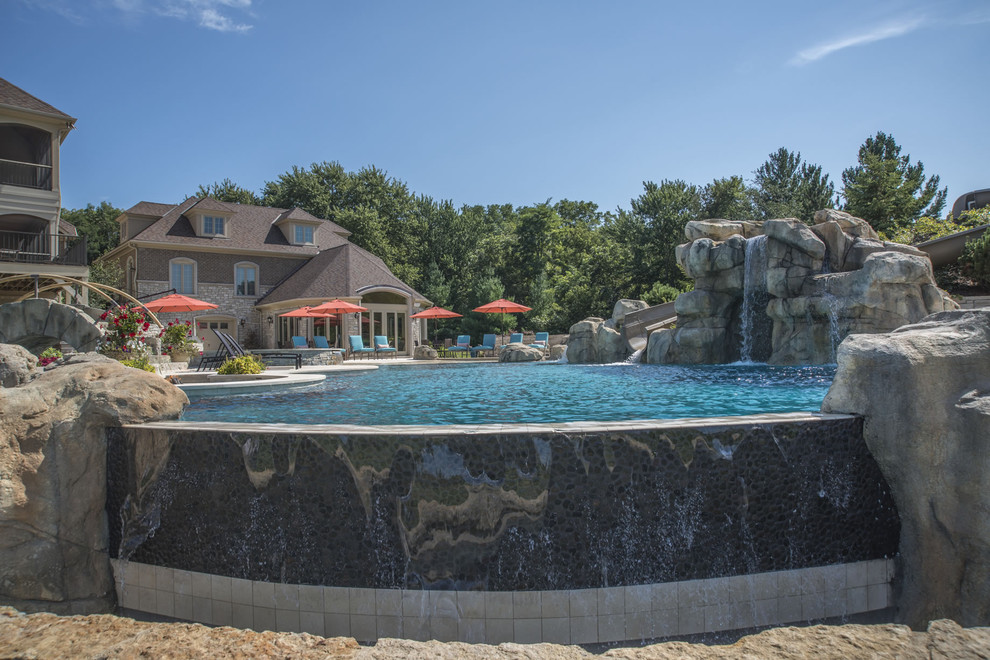 Huge backyard stone and custom-shaped infinity pool fountain photo in Chicago