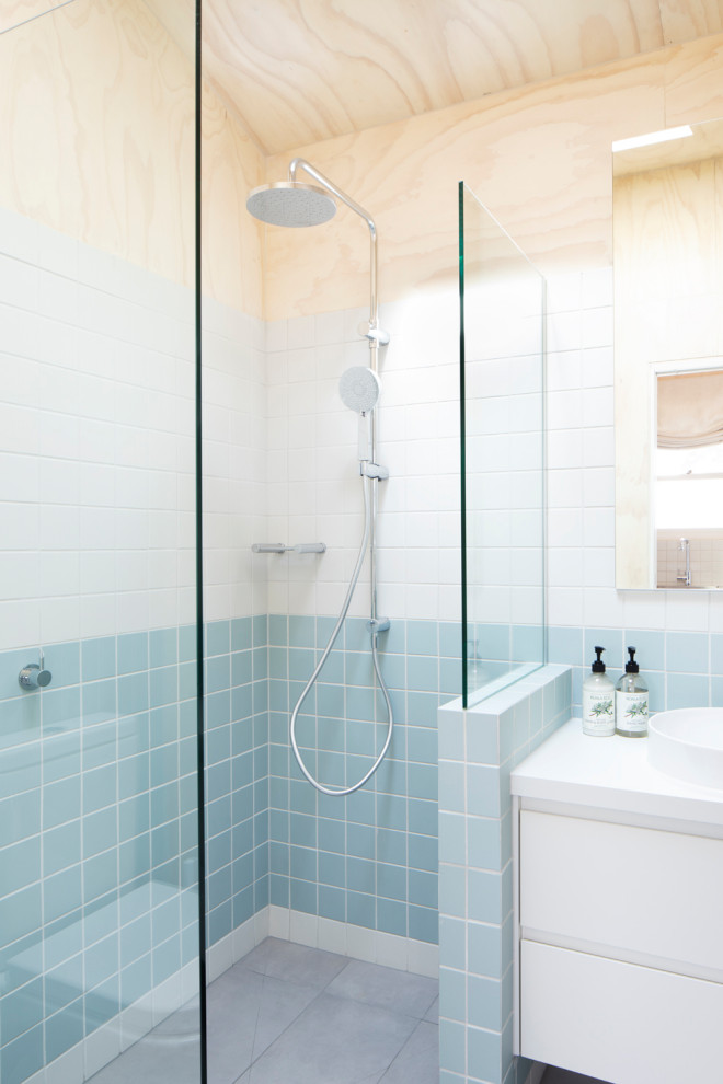 Photo of a small contemporary shower room bathroom in Melbourne with flat-panel cabinets, white cabinets, a walk-in shower, a two-piece toilet, blue tiles, porcelain tiles, white walls, porcelain flooring, a vessel sink, laminate worktops, grey floors, an open shower, white worktops, a single sink, a built in vanity unit, a wood ceiling and wood walls.