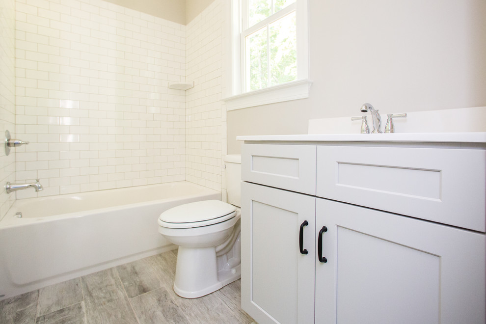 Mid-sized country 3/4 bathroom in Other with shaker cabinets, white cabinets, an alcove tub, a shower/bathtub combo, beige walls, light hardwood floors, an integrated sink, brown floor and a shower curtain.