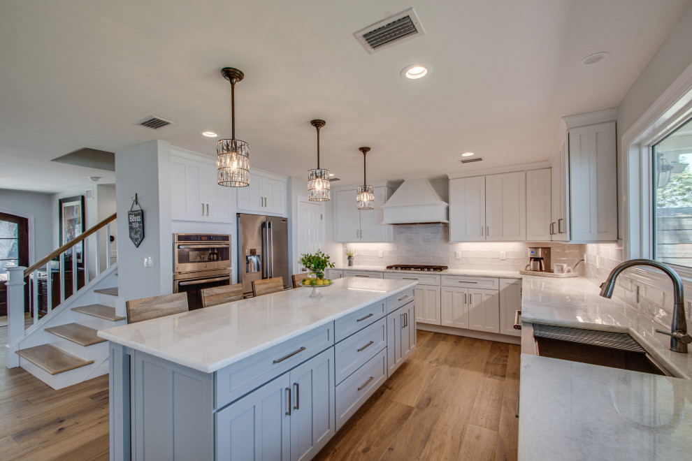Inspiration for a large transitional u-shaped kitchen in Other with a farmhouse sink, recessed-panel cabinets, white cabinets, white splashback, shiplap splashback, stainless steel appliances, with island, beige floor and white benchtop.