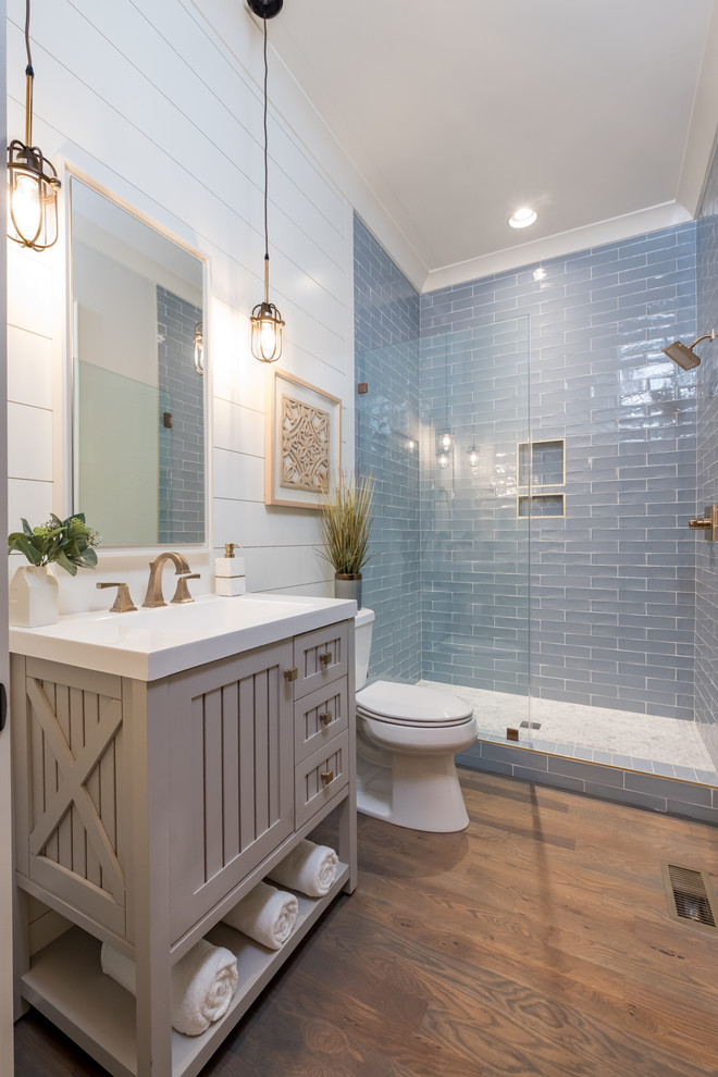 Mid-sized country bathroom in Charlotte with blue tile, glass tile, beige walls, medium hardwood floors and a hinged shower door.