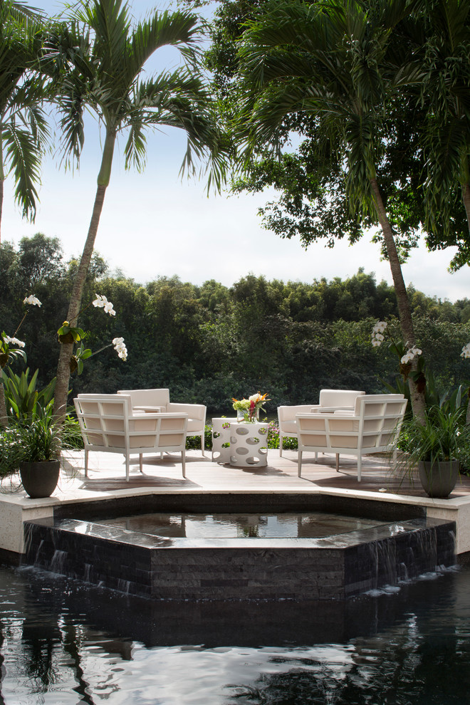 Inspiration for a mid-sized contemporary backyard patio in Miami with natural stone pavers and no cover.