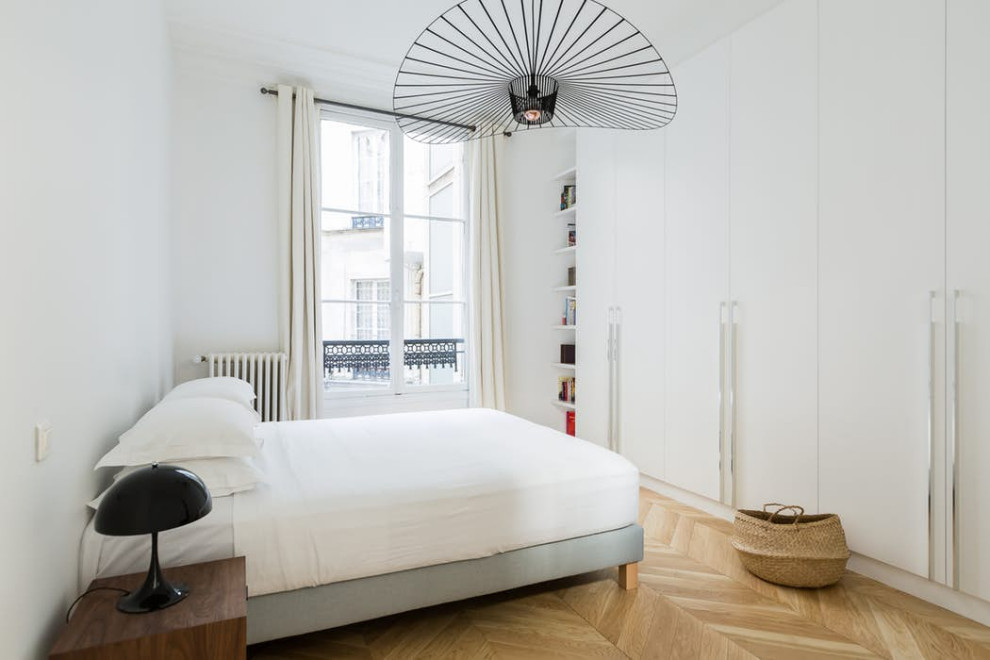 This is an example of a transitional bedroom in Paris with light hardwood floors.