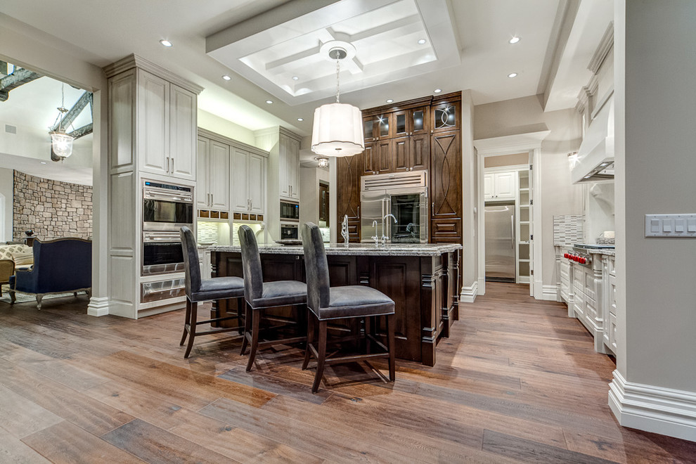 Example of a transitional medium tone wood floor kitchen design in Calgary with raised-panel cabinets, distressed cabinets, stainless steel appliances and an island