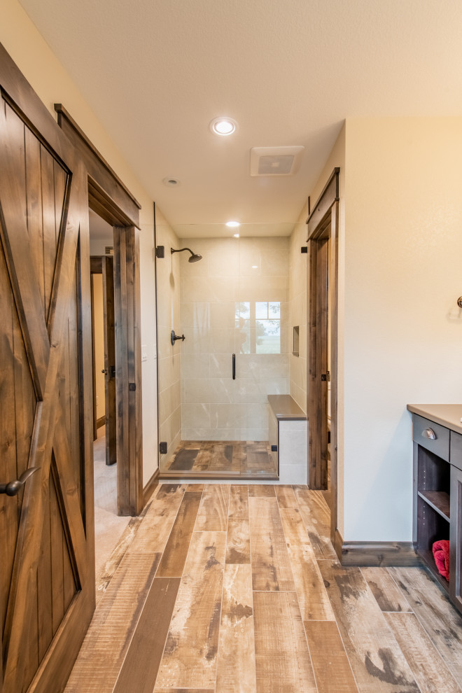 This is an example of a mid-sized bathroom in Denver with dark wood cabinets, brown tile, wood-look tile, beige walls, ceramic floors, brown floor, a hinged shower door, beige benchtops, an enclosed toilet, a double vanity, a built-in vanity and wood walls.