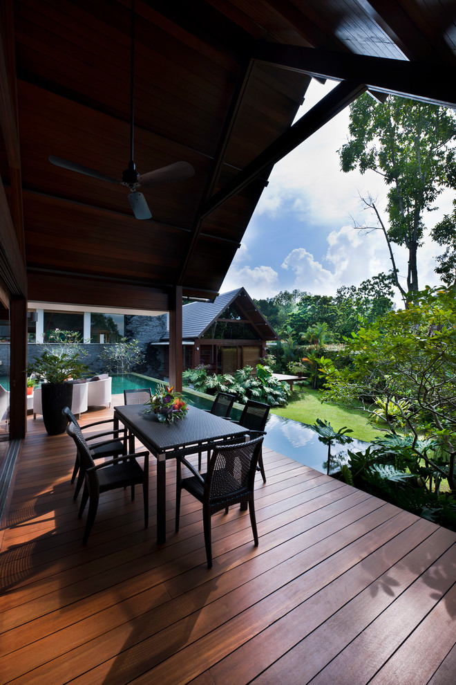 Photo of a tropical backyard patio in Singapore with decking and a roof extension.