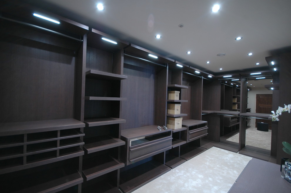 This is an example of a mid-sized contemporary walk-in wardrobe in Dorset with dark wood cabinets.