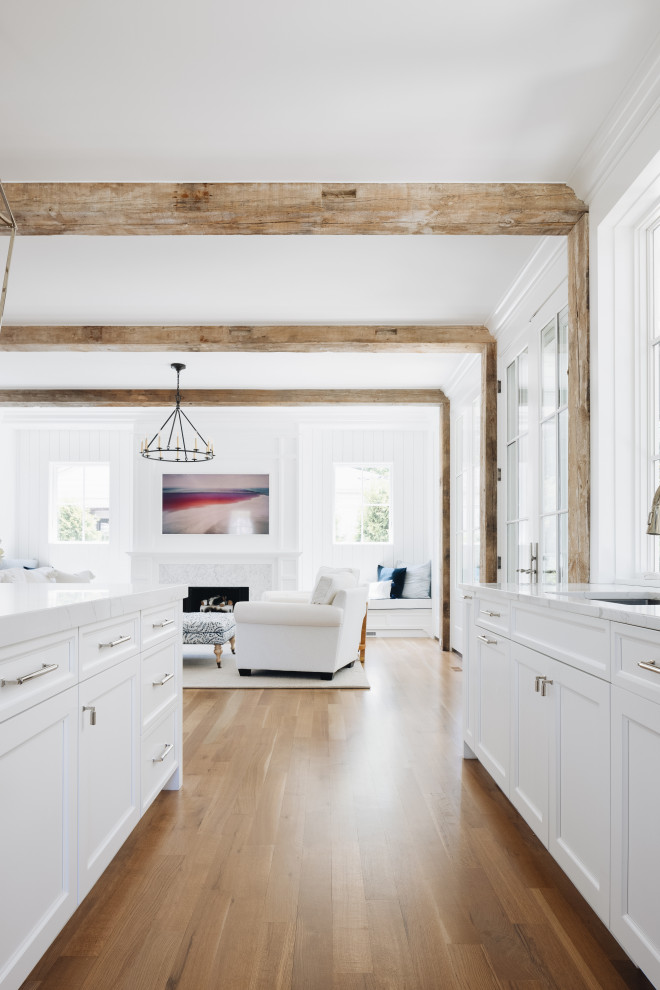 South Coast Farmhouse - Reclaimed Wisconsin barn beams delineating spaces for the kitchen and living areas. A unique, white-washed brick kitchen backsplash and banquet eat-in seating area. Wine storage and hidden door refrigerator.
