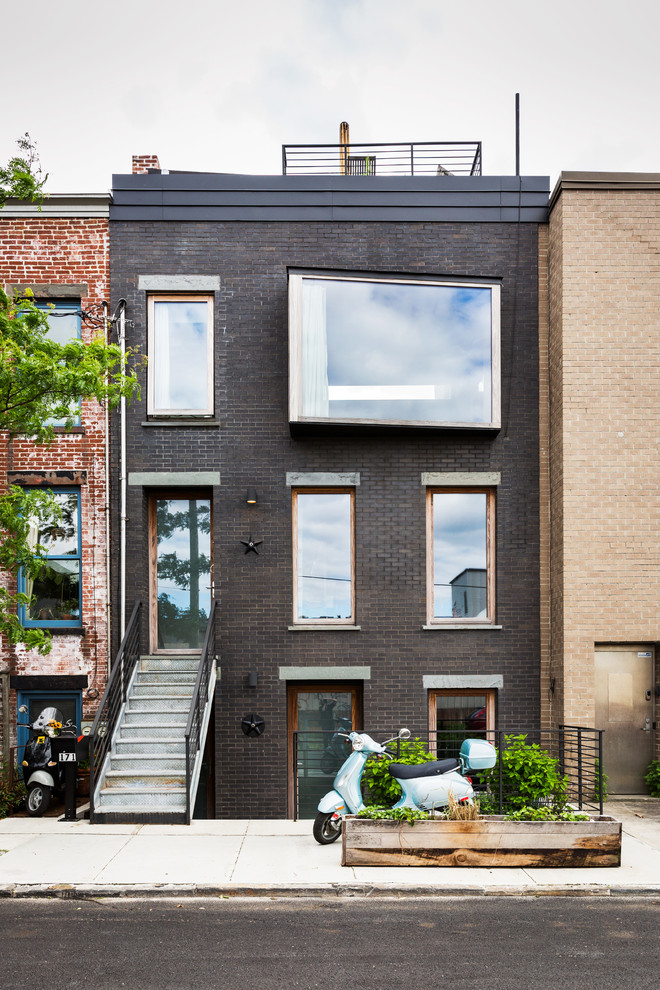 This is an example of an industrial three-storey brick townhouse exterior in New York with a flat roof.