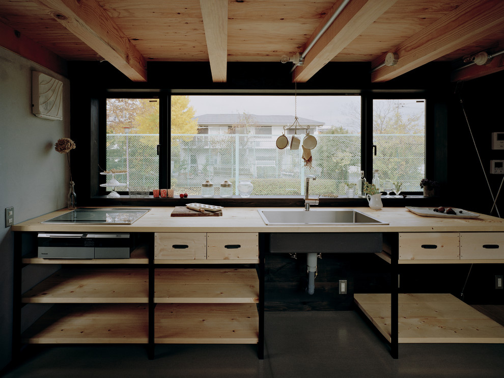 This is an example of an industrial kitchen in Other with a drop-in sink, open cabinets, light wood cabinets, wood benchtops, stainless steel appliances and no island.