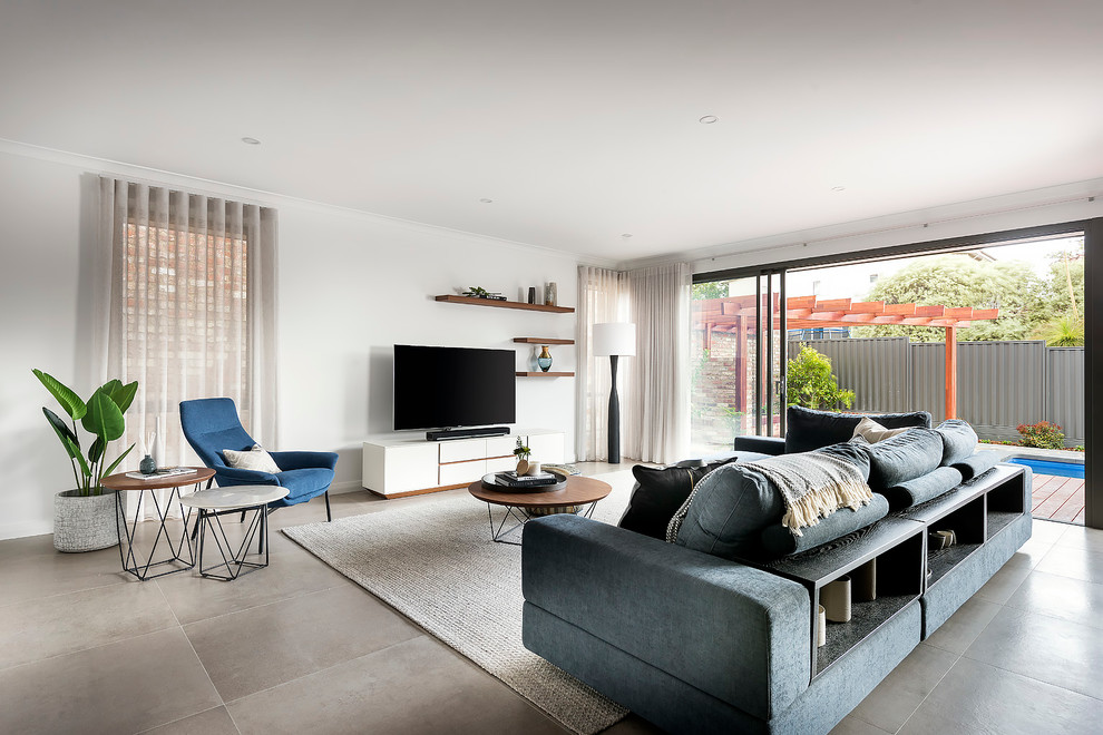 This is an example of a large modern open concept living room in Perth with white walls, porcelain floors and a freestanding tv.