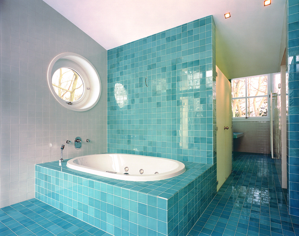 This is an example of a large contemporary bathroom in Hamburg with a drop-in tub, blue tile and blue walls.