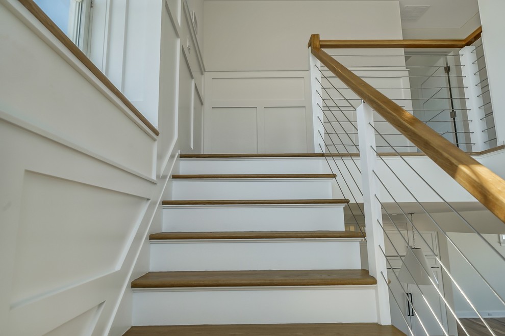 Photo of a beach style wood l-shaped staircase in New York with wood risers and cable railing.