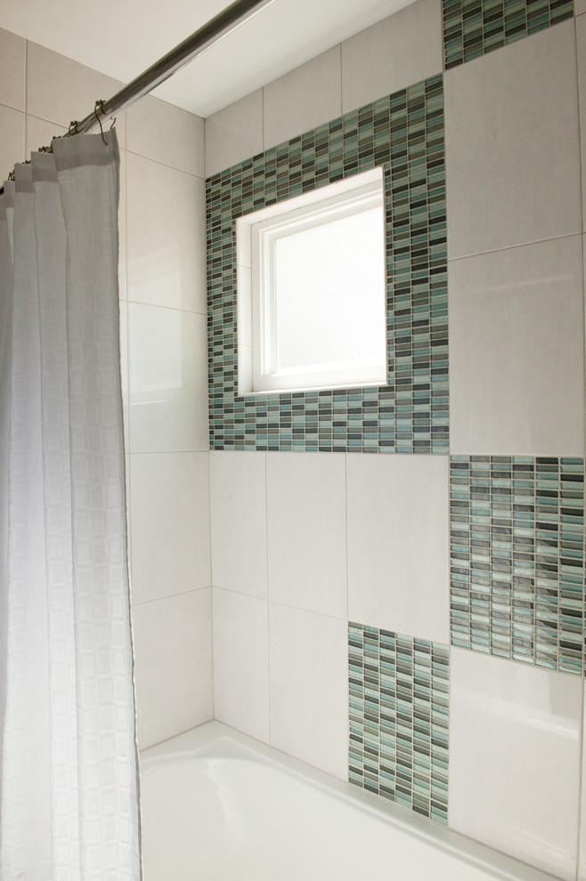 Photo of a mid-sized modern kids bathroom in Austin with an integrated sink, shaker cabinets, grey cabinets, solid surface benchtops, an alcove tub, a shower/bathtub combo, blue tile, glass tile, blue walls and ceramic floors.