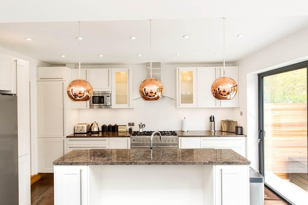 Mid-sized contemporary l-shaped open plan kitchen in London with an undermount sink, shaker cabinets, white cabinets, granite benchtops and with island.