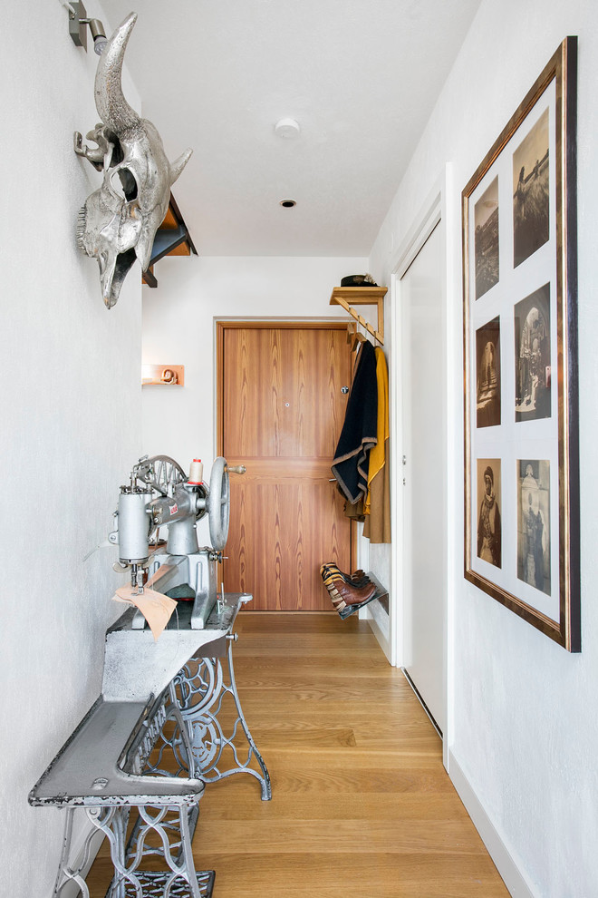 This is an example of a mid-sized eclectic hallway in Malmo with white walls and light hardwood floors.