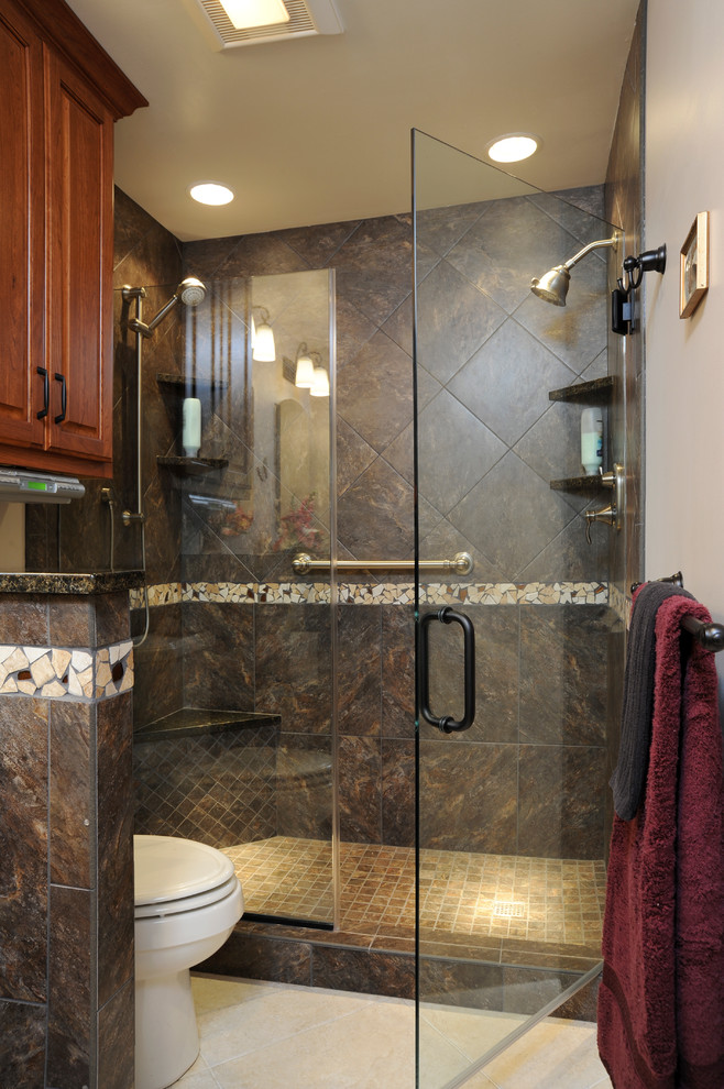 Inspiration for a mid-sized contemporary 3/4 bathroom in Cincinnati with raised-panel cabinets, dark wood cabinets, an alcove shower, a two-piece toilet, gray tile, ceramic tile, grey walls, limestone floors, an undermount sink, granite benchtops, beige floor and a hinged shower door.