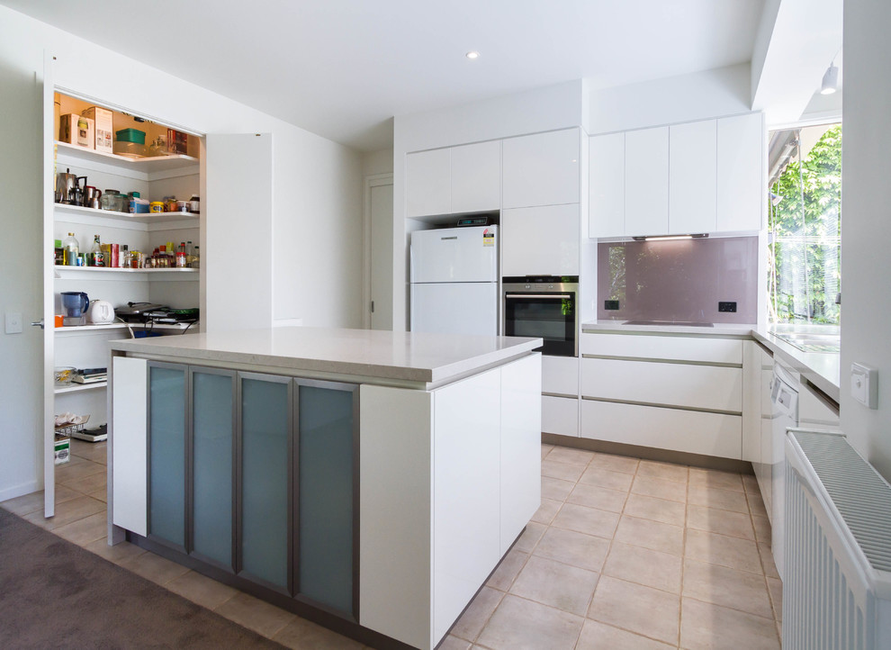 This is an example of a mid-sized modern u-shaped eat-in kitchen in Melbourne with a double-bowl sink, flat-panel cabinets, white cabinets, quartz benchtops, glass sheet splashback and with island.