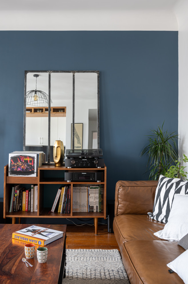 На фото: открытая гостиная комната среднего размера в современном стиле с с книжными шкафами и полками, синими стенами и паркетным полом среднего тона