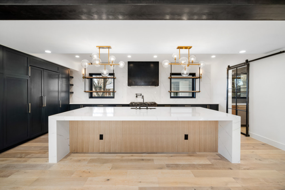 Large urban u-shaped light wood floor, brown floor and exposed beam open concept kitchen photo in Denver with an undermount sink, shaker cabinets, black cabinets, quartzite countertops, white backsplash, quartz backsplash, paneled appliances, an island and white countertops