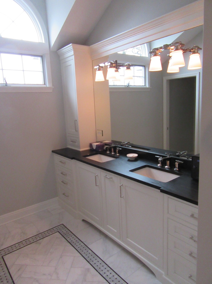 Mid-sized contemporary master bathroom in Chicago with a corner shower, a two-piece toilet, white tile, marble floors, an undermount sink, a hinged shower door, black benchtops, furniture-like cabinets, white cabinets, ceramic tile, blue walls, tile benchtops and grey floor.
