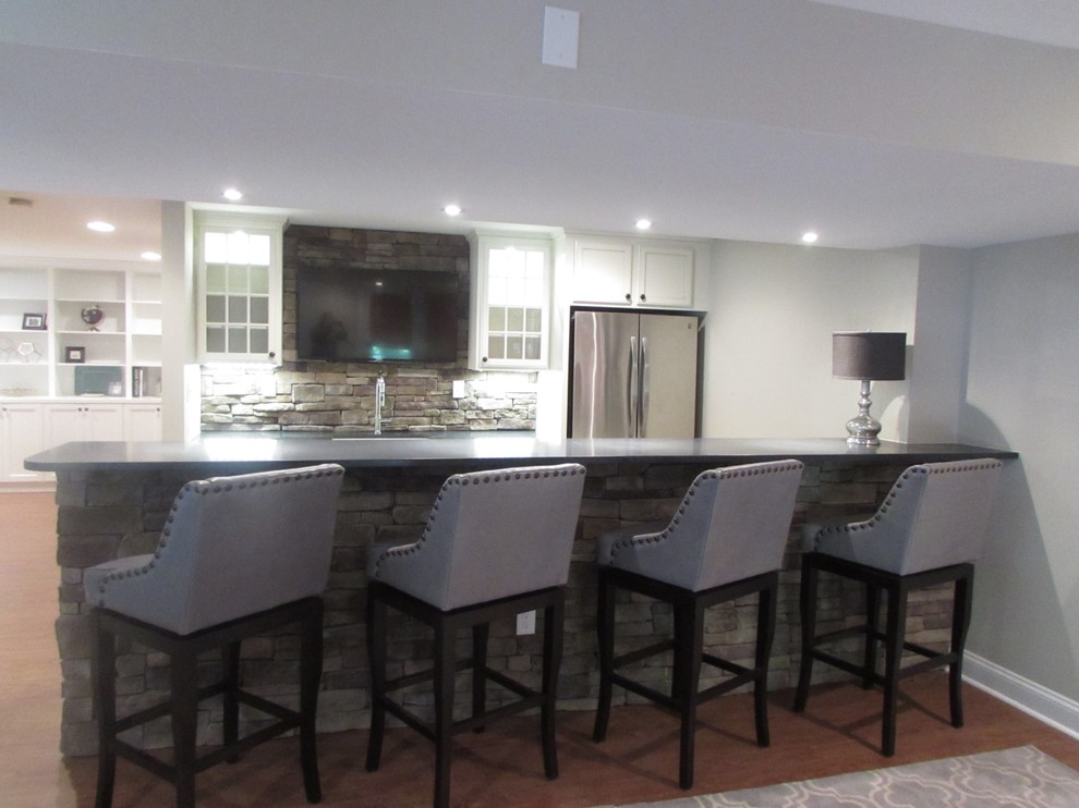 Inspiration for a large walk-out vinyl floor basement remodel with beige walls, a standard fireplace and a stone fireplace