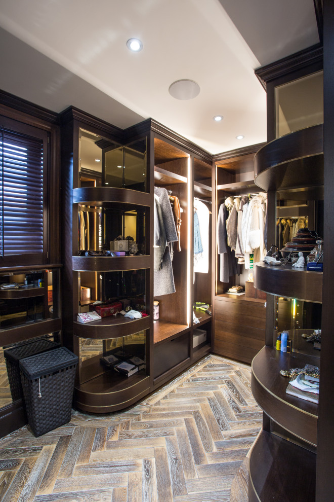 This is an example of a mid-sized modern gender-neutral walk-in wardrobe in London with open cabinets, dark wood cabinets, medium hardwood floors and brown floor.
