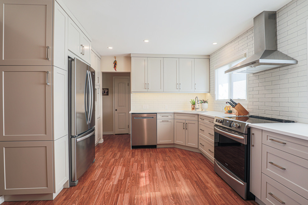 Inspiration for a mid-sized transitional l-shaped vinyl floor and brown floor eat-in kitchen remodel in Edmonton with an undermount sink, shaker cabinets, beige cabinets, quartz countertops, white backsplash, ceramic backsplash, stainless steel appliances, no island and white countertops