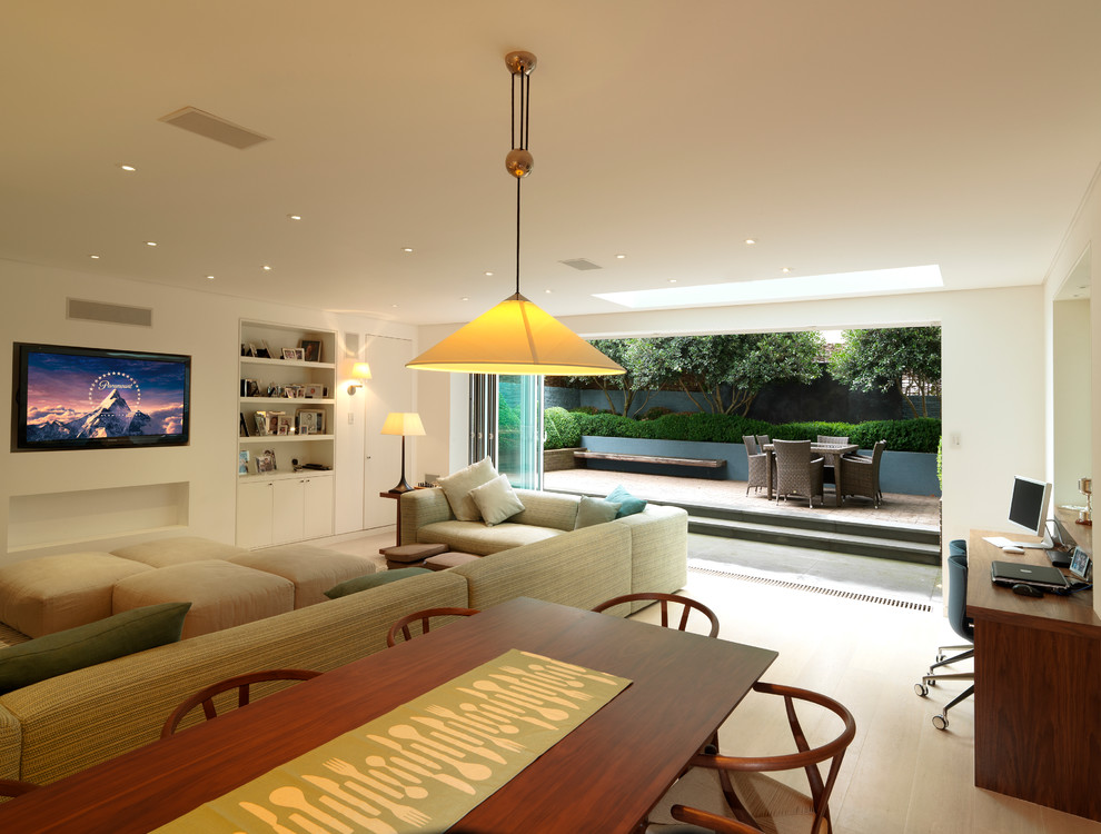 This is an example of a mid-sized contemporary open concept living room in London with beige walls and a wall-mounted tv.