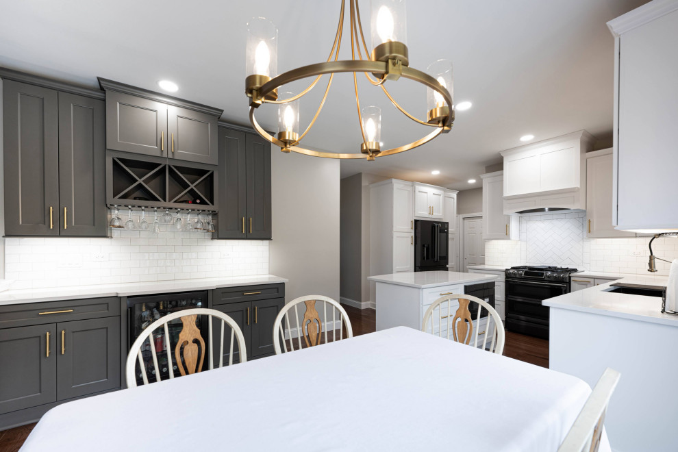 This is an example of a large transitional u-shaped eat-in kitchen in Other with an undermount sink, shaker cabinets, white cabinets, quartz benchtops, white splashback, black appliances, dark hardwood floors, with island and white benchtop.