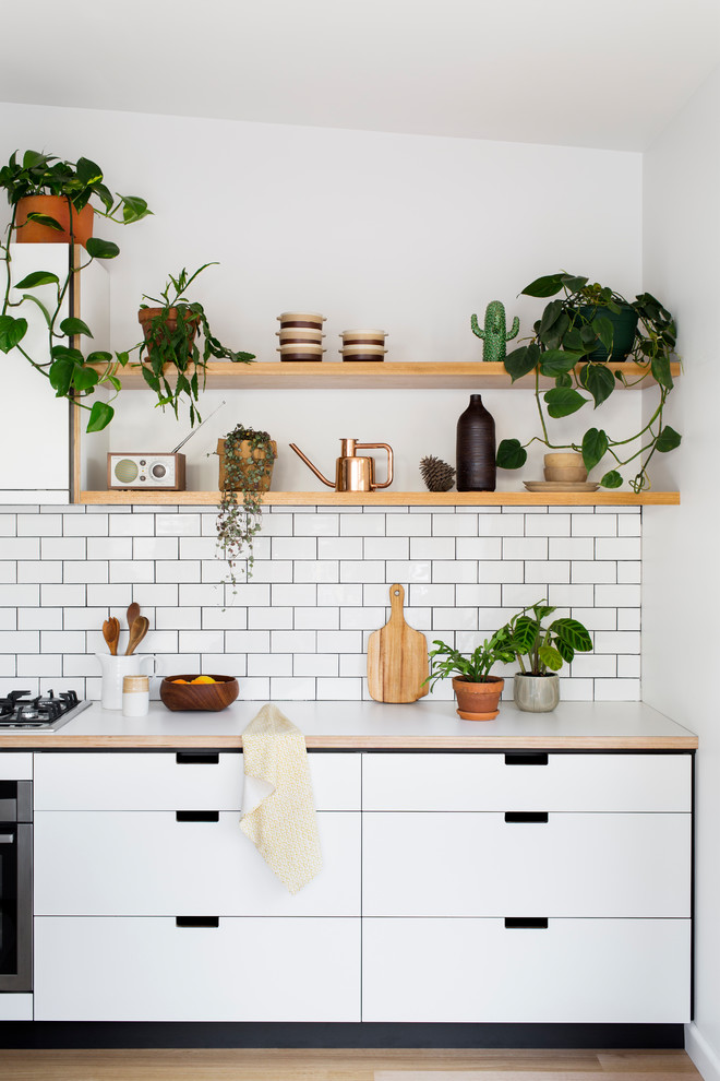 Design ideas for a mid-sized scandinavian kitchen in Melbourne with flat-panel cabinets, white cabinets, white splashback, subway tile splashback and light hardwood floors.