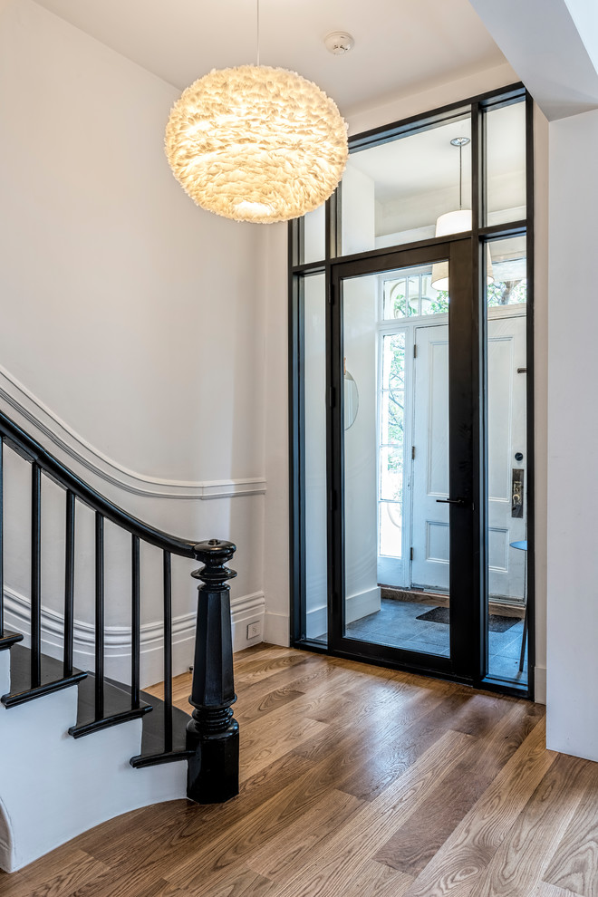 Inspiration for a transitional vestibule in Boston with white walls, medium hardwood floors, a single front door, a glass front door and brown floor.