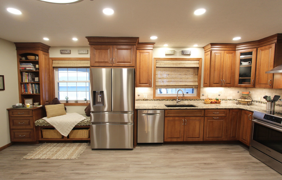 This is an example of a mid-sized transitional galley eat-in kitchen in Cleveland with an undermount sink, raised-panel cabinets, medium wood cabinets, quartz benchtops, beige splashback, limestone splashback, stainless steel appliances, vinyl floors, a peninsula, grey floor and beige benchtop.