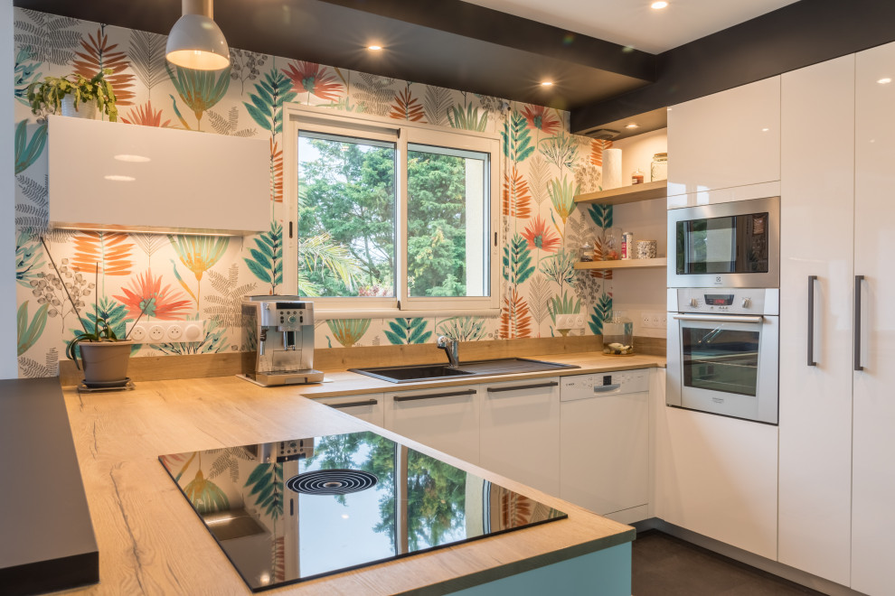 This is an example of a medium sized modern u-shaped kitchen/diner in Other with a single-bowl sink, flat-panel cabinets, white cabinets, wood worktops, wood splashback, stainless steel appliances, a breakfast bar and a drop ceiling.