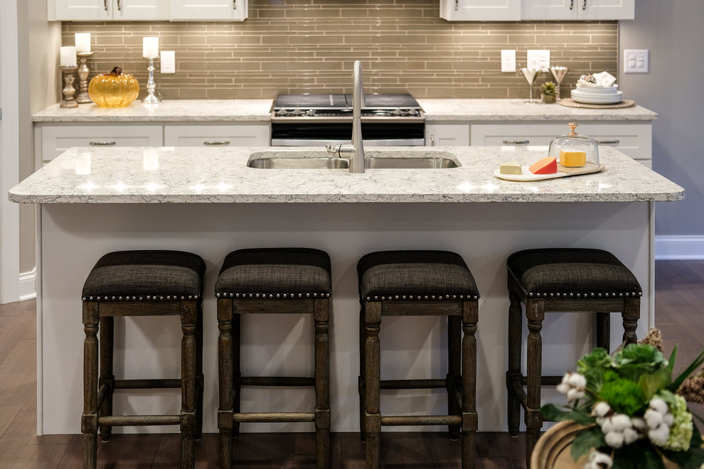 Mid-sized transitional l-shaped dark wood floor and brown floor eat-in kitchen photo with an undermount sink, recessed-panel cabinets, white cabinets, quartz countertops, brown backsplash, stainless steel appliances, an island and white countertops