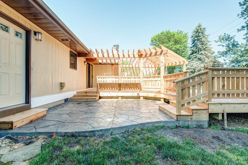 Example of a large transitional backyard deck design in Chicago with a pergola