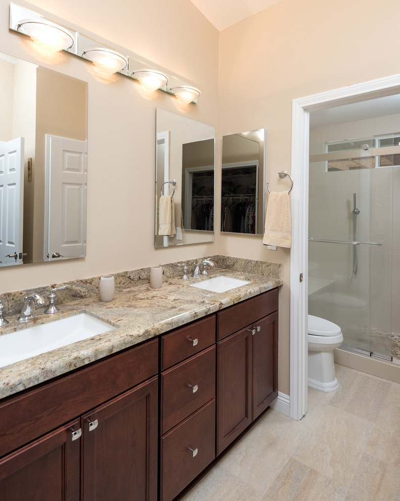 Large traditional master bathroom in San Diego with recessed-panel cabinets, a corner shower, a two-piece toilet, beige tile, quartzite benchtops, dark wood cabinets, beige walls, porcelain floors, porcelain tile, an undermount sink, beige floor, a sliding shower screen, beige benchtops, a double vanity and a built-in vanity.