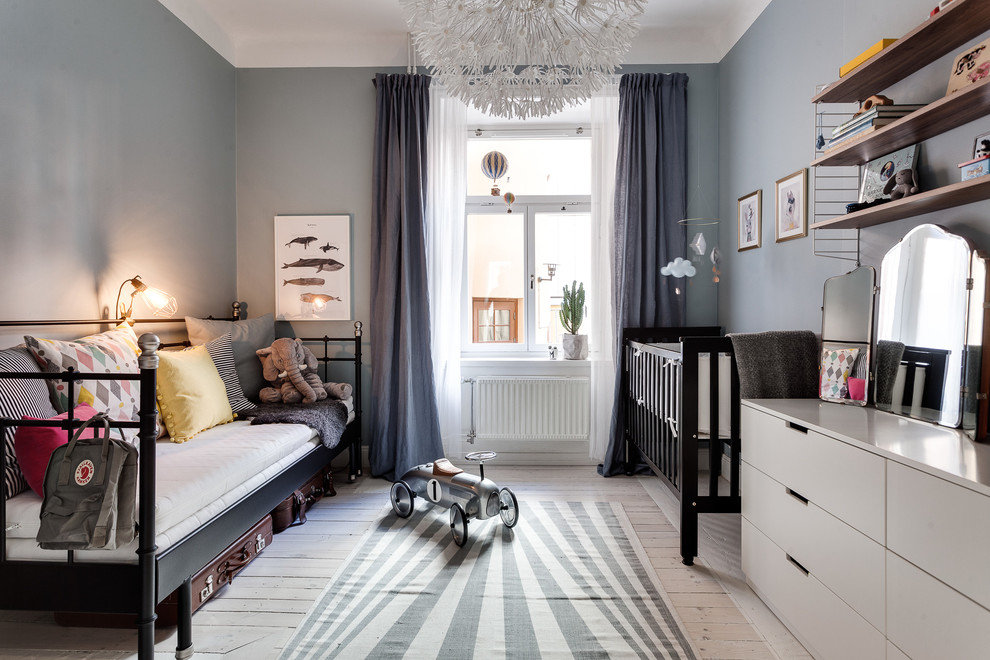 Design ideas for a mid-sized transitional gender-neutral nursery in Stockholm with grey walls and light hardwood floors.